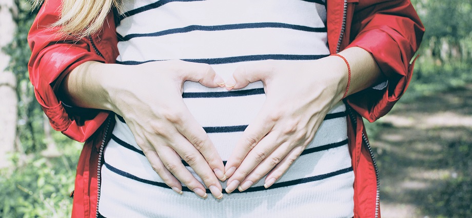 Pregnant woman experiencing symptoms of pregnancy rhinitis, holding tissue near her nose